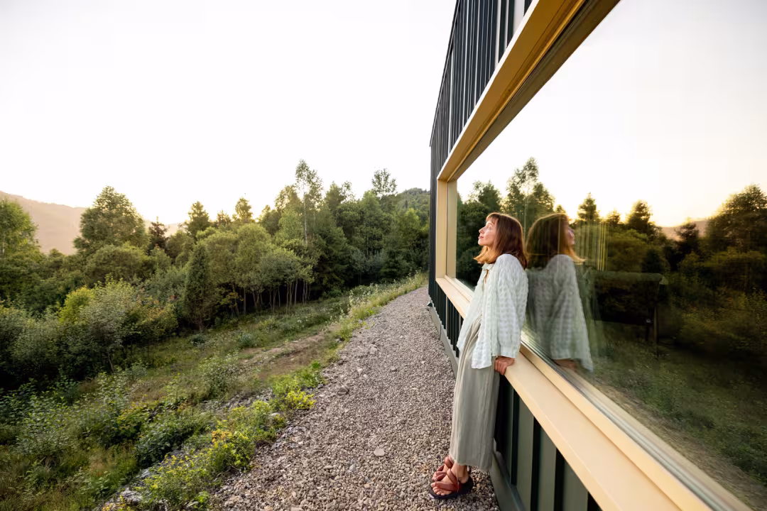 Tevreden vrouw kijkt uit over haar ruime, groene achtertuin.